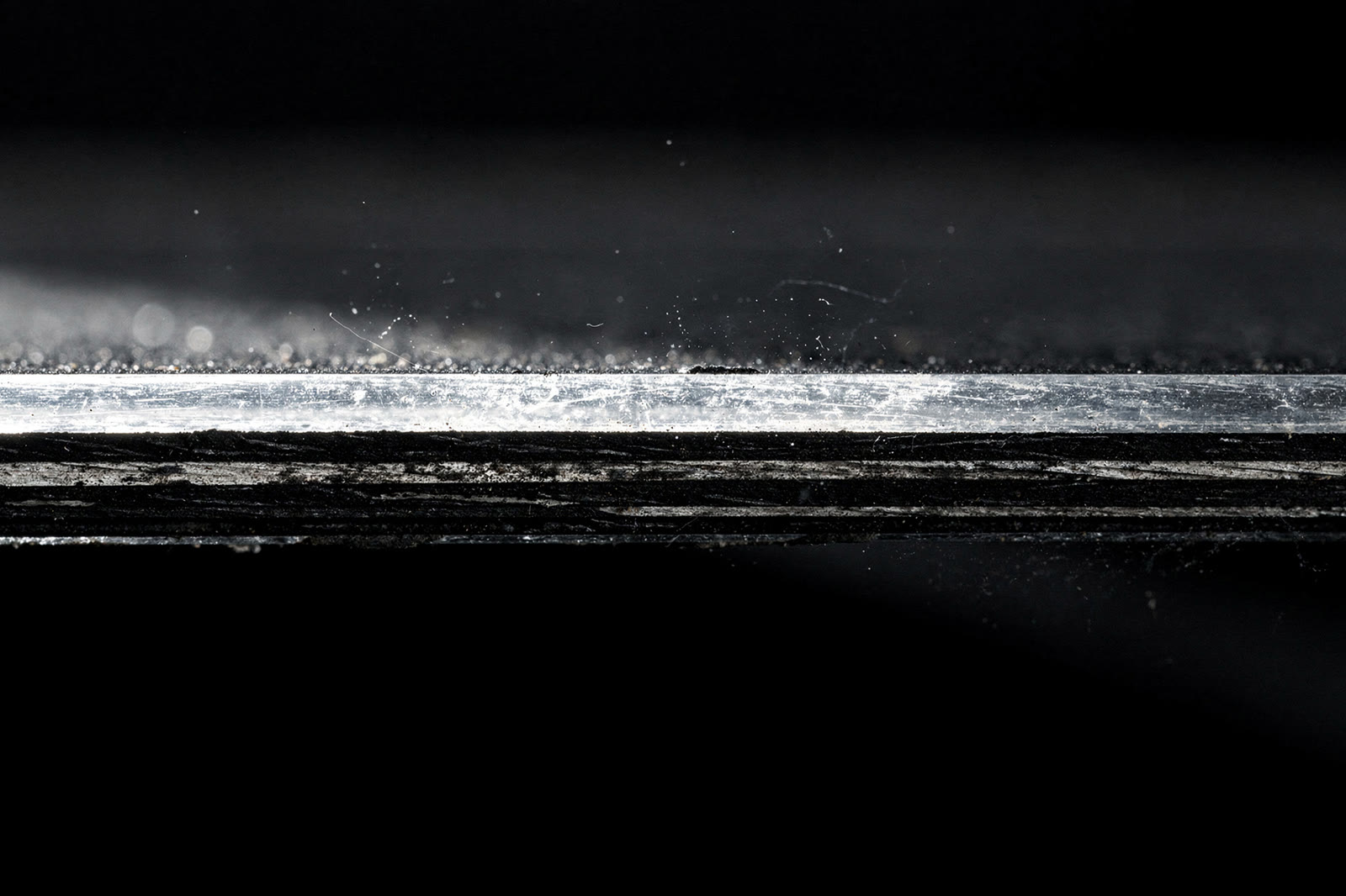 Linha de reflexo sobre a pintura escura com marcas residuais ao longo da borracha.